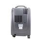 Gray medical oxygen concentrator with handle, ventilation grid, wheels, and control panel on front.