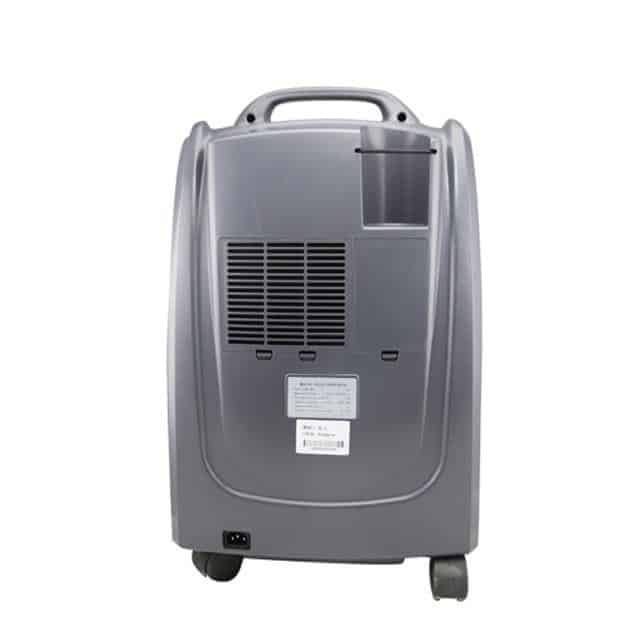 Gray medical oxygen concentrator with handle, ventilation grid, wheels, and control panel on front.