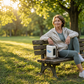 Airlux portable oxygen concentrator in beige carrying case on bench next to woman wearing nasal cannula.