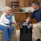 Black DeVilbiss 5 Litre home oxygen concentrator with control panel and flow meter, next to seated elderly woman and